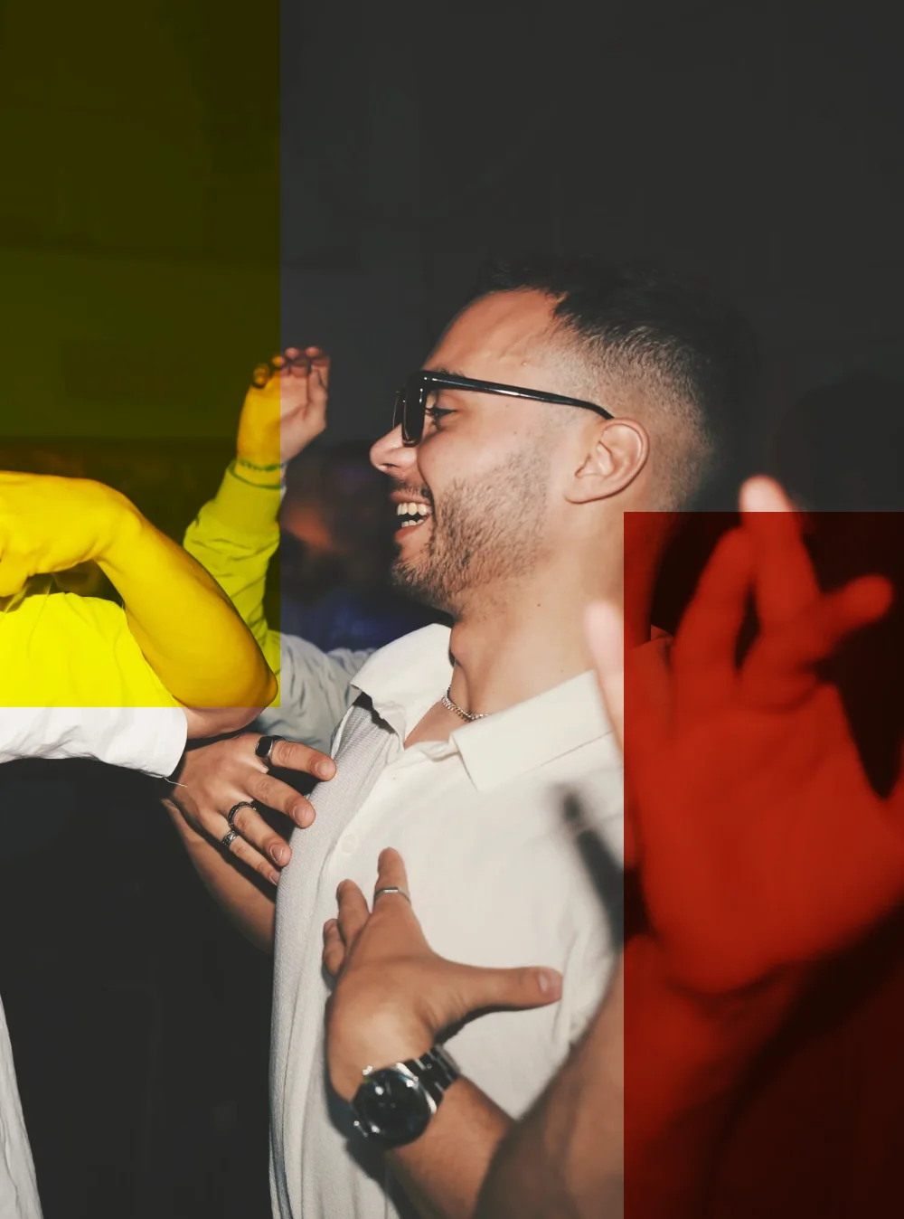 A man in glasses laughing among raised hands