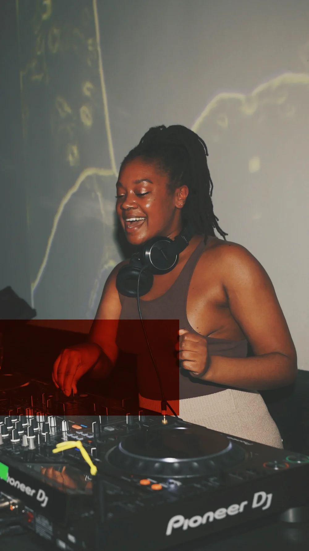 A DJ smiling at the decks, projections on the wall behind