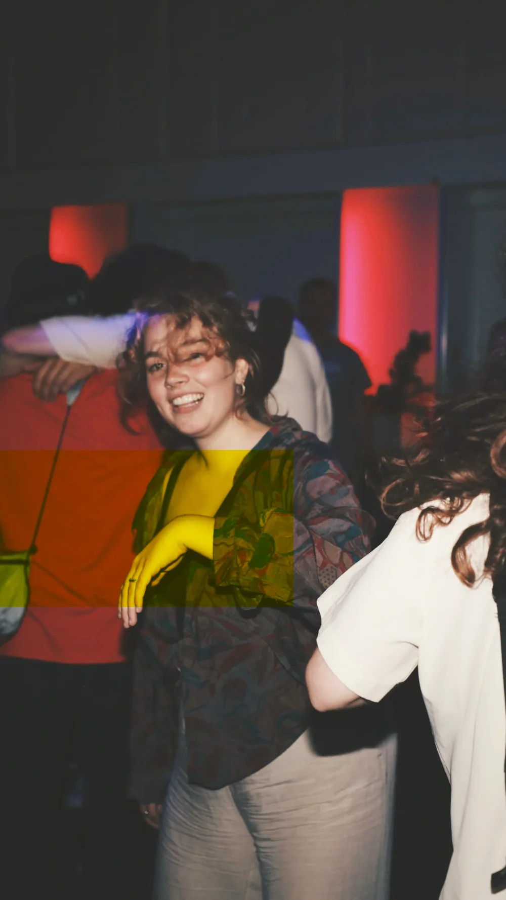 A woman laughing on the dance floor, red light behind her