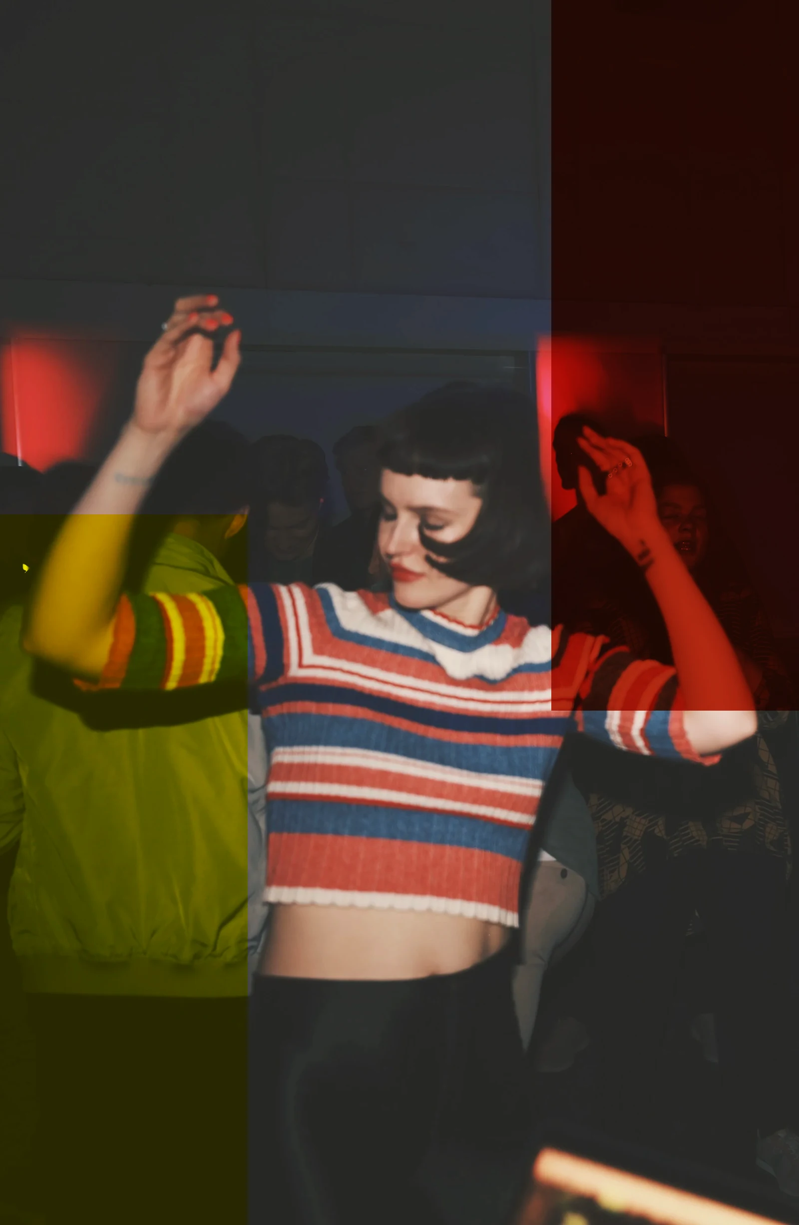 A woman in a striped top dancing, red light behind
