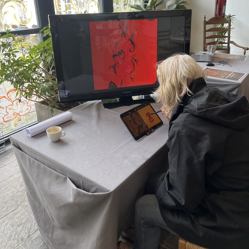 A visitor drawing at the installation, the screen beside them